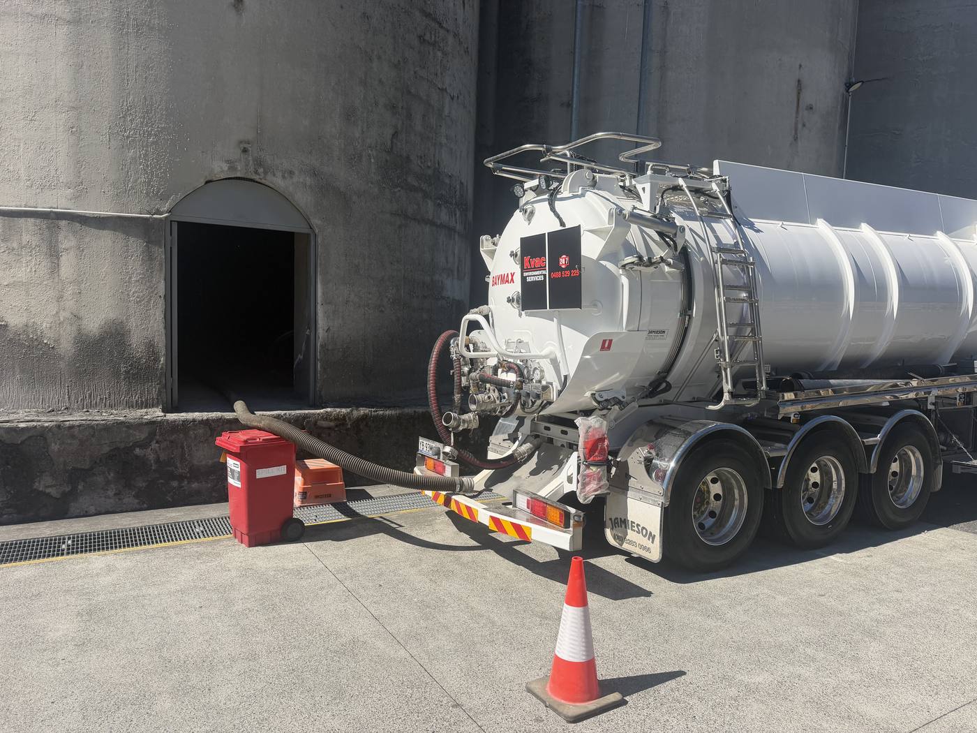 KVAC vacuum truck Baymax hose-feeding into a silo access point with spill kit staged on site