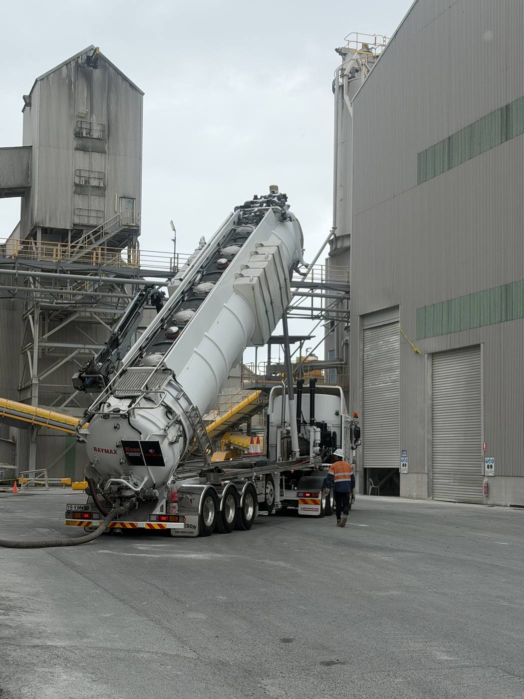 KVAC vacuum truck Baymax with tank raised, discharging at an industrial batching plant