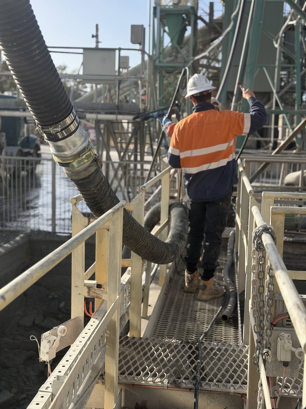 KVAC operator running vacuum hose across an elevated industrial platform