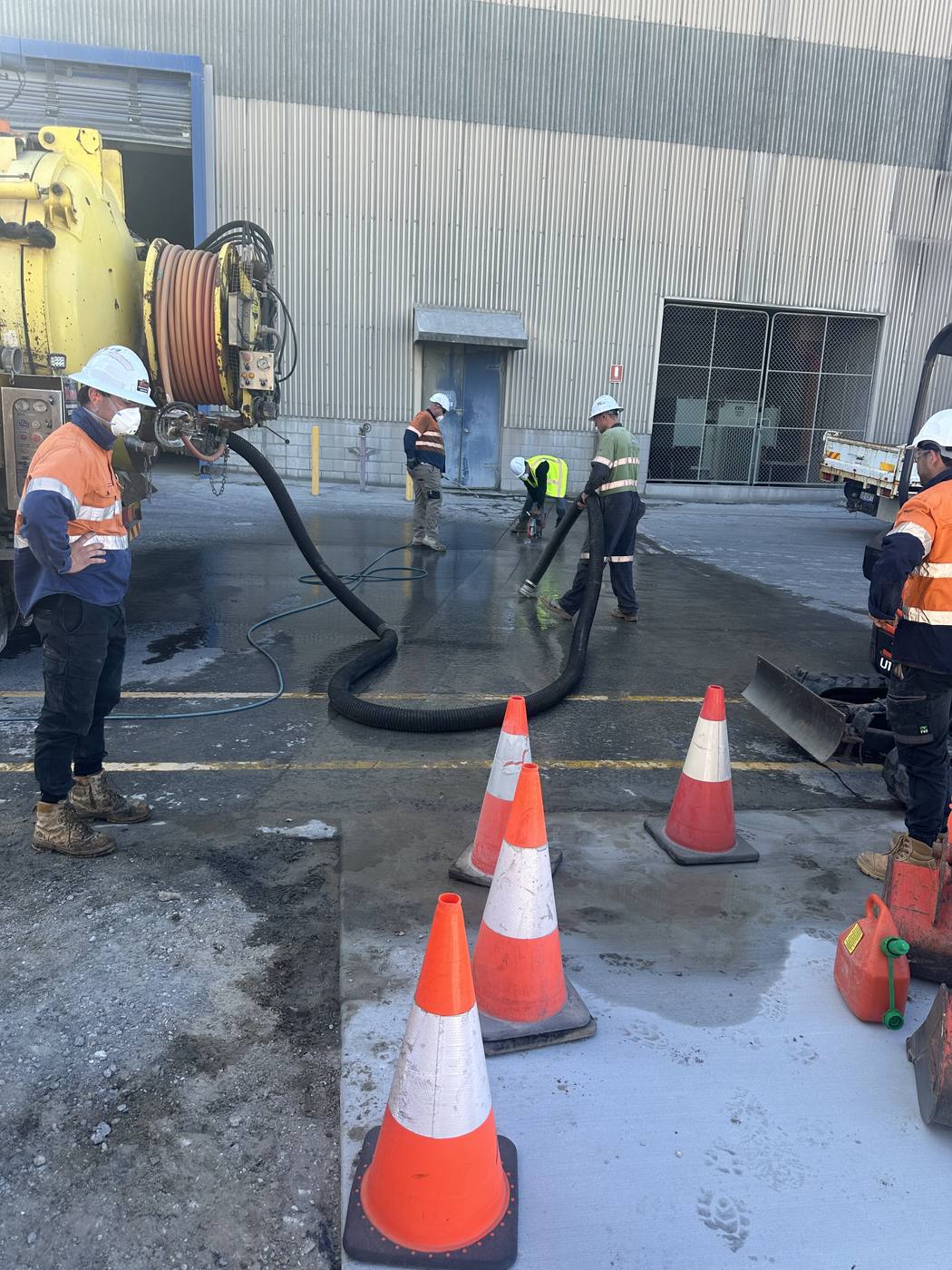 KVAC crew running a high-pressure jetting and vacuum job with traffic cones set up on site