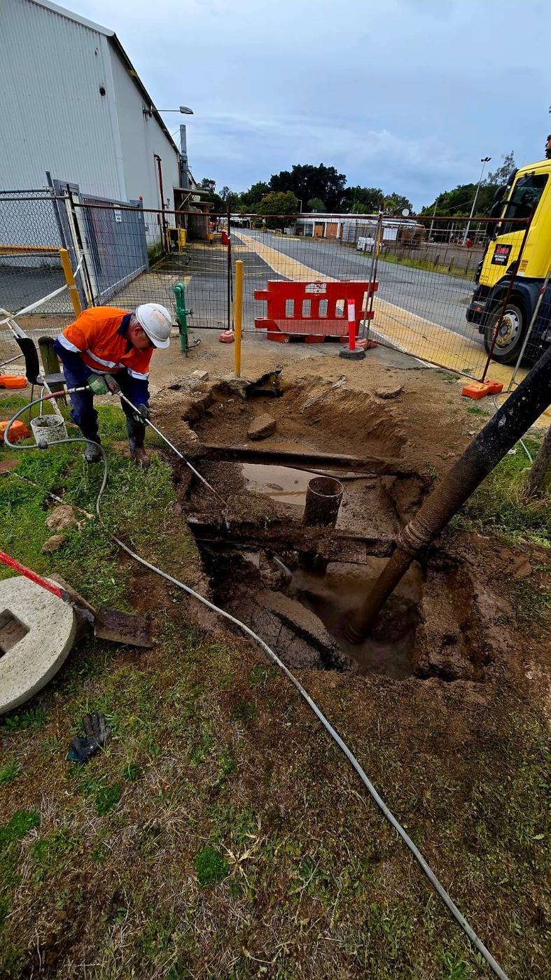 KVAC operator hydro-excavating a service pit on a fenced worksite