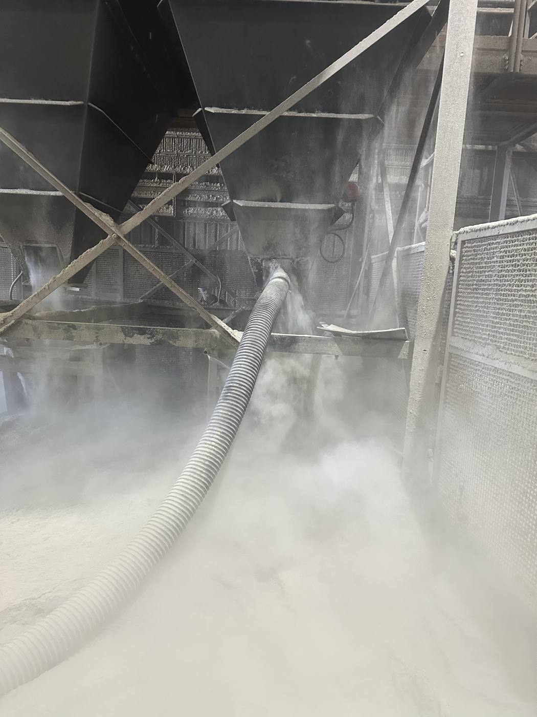 Vacuum hose feeding bulk powder into an industrial hopper during a discharge job